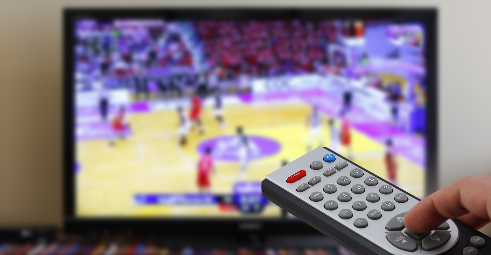 Man using remote control with the basketball game