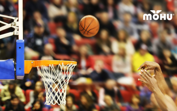 Basketball going into hoop with crowd watching in the background and Mohu logo