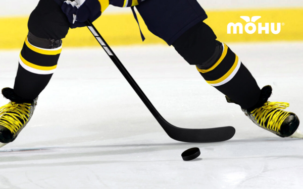 Hockey player on the ice hitting the puck with Mohu logo