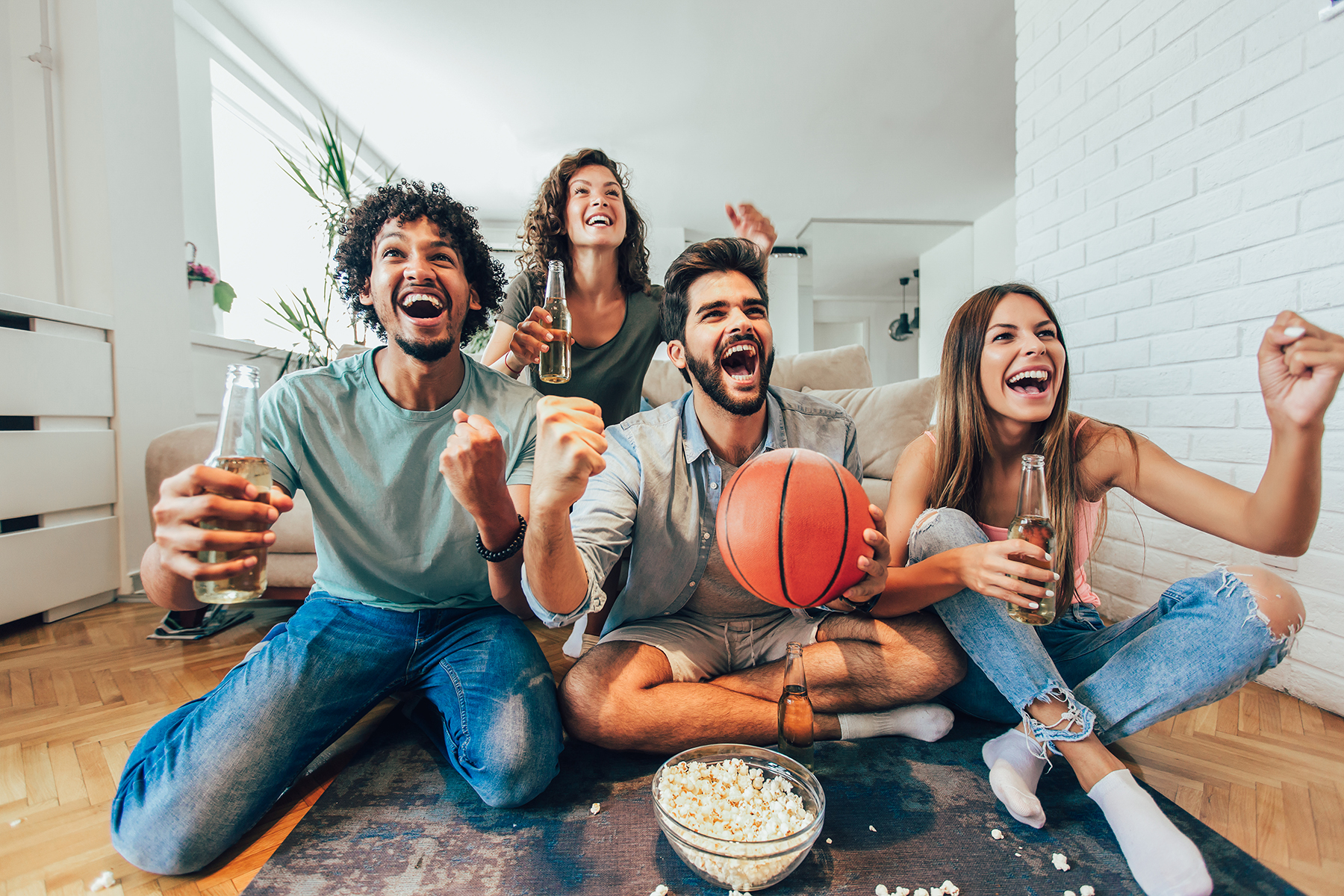 group of friends watching the basketball game with extreme excitement while eating and drinking