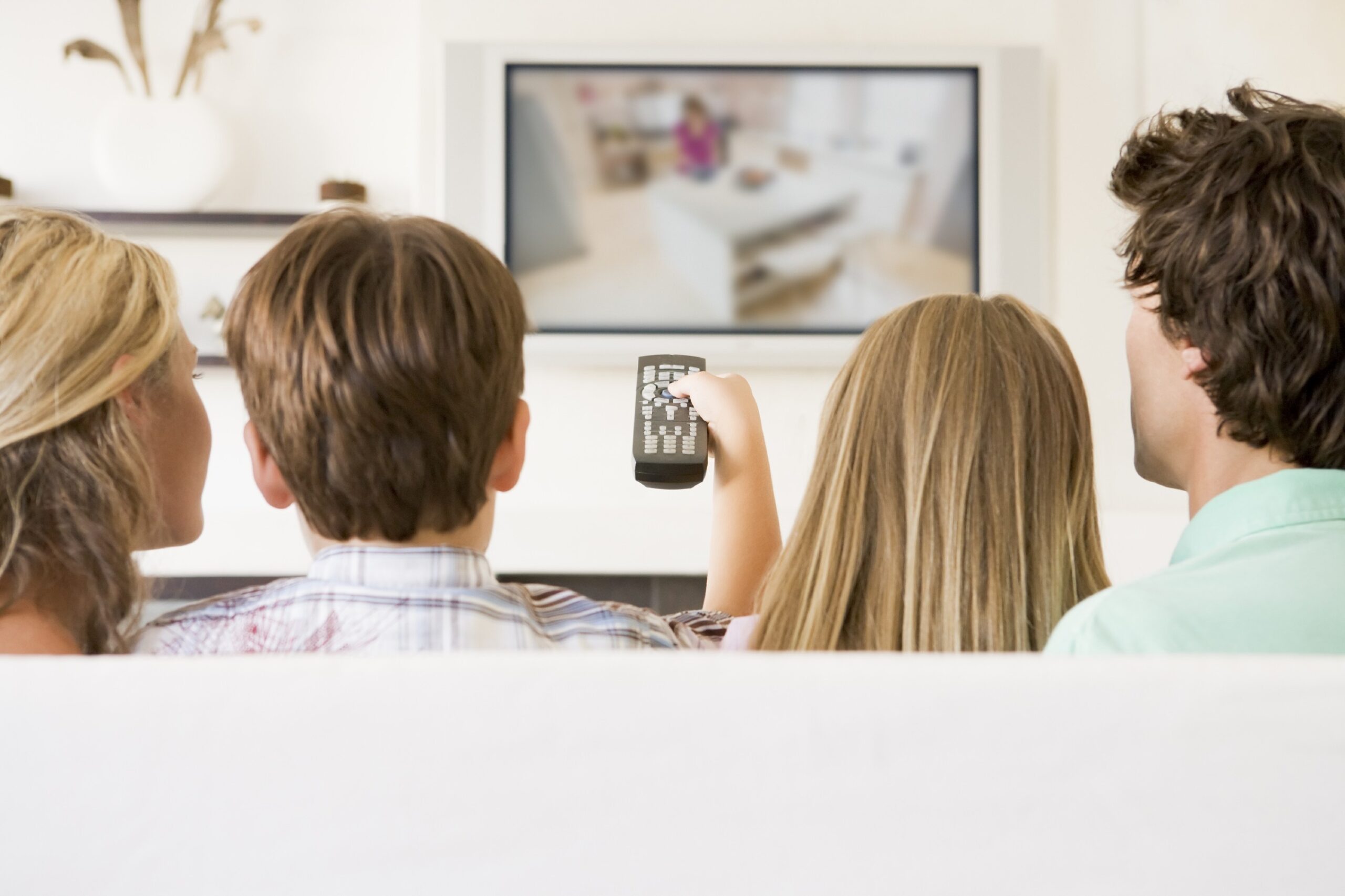 family watching TV while son holds the remote to change channels